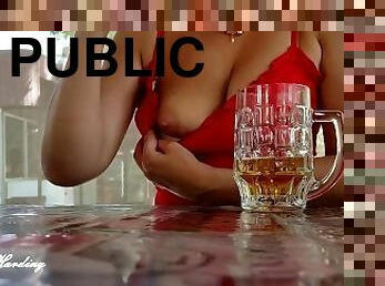 Alice sits in a public street cafe with two glasses of beer and shows passers-by her big tits
