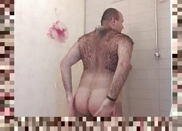 Hairy bear washes himself in the shower