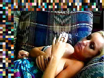 Chubby blonde is smoking a cigarette on sofa